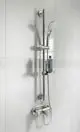 Brausekombination von Ideal Standard mit Handbrause, Wandhalterung und verchromtem Finish, montiert an einer weißen gefliesten Wand.